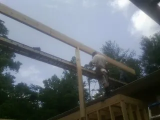Carpenter setting a ridge beam over a new addition frame — Ice Dam Removal by Roofing Brothers in Oak Hall