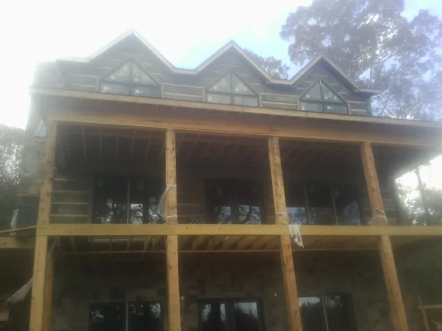 Dormers and porch framing on a large log home under construction — Roof Coating work by our crew in Oak Hall