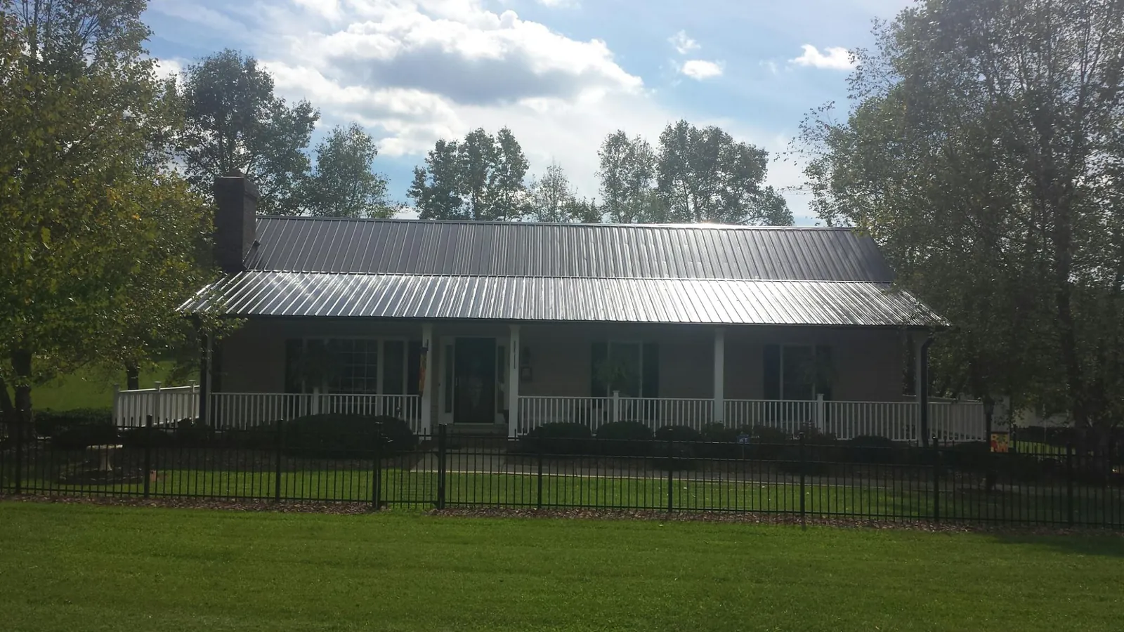 Gray metal roof on a brick ranch with a full width front porch — Gutter Guard Installation work by our crew in Oak Hall