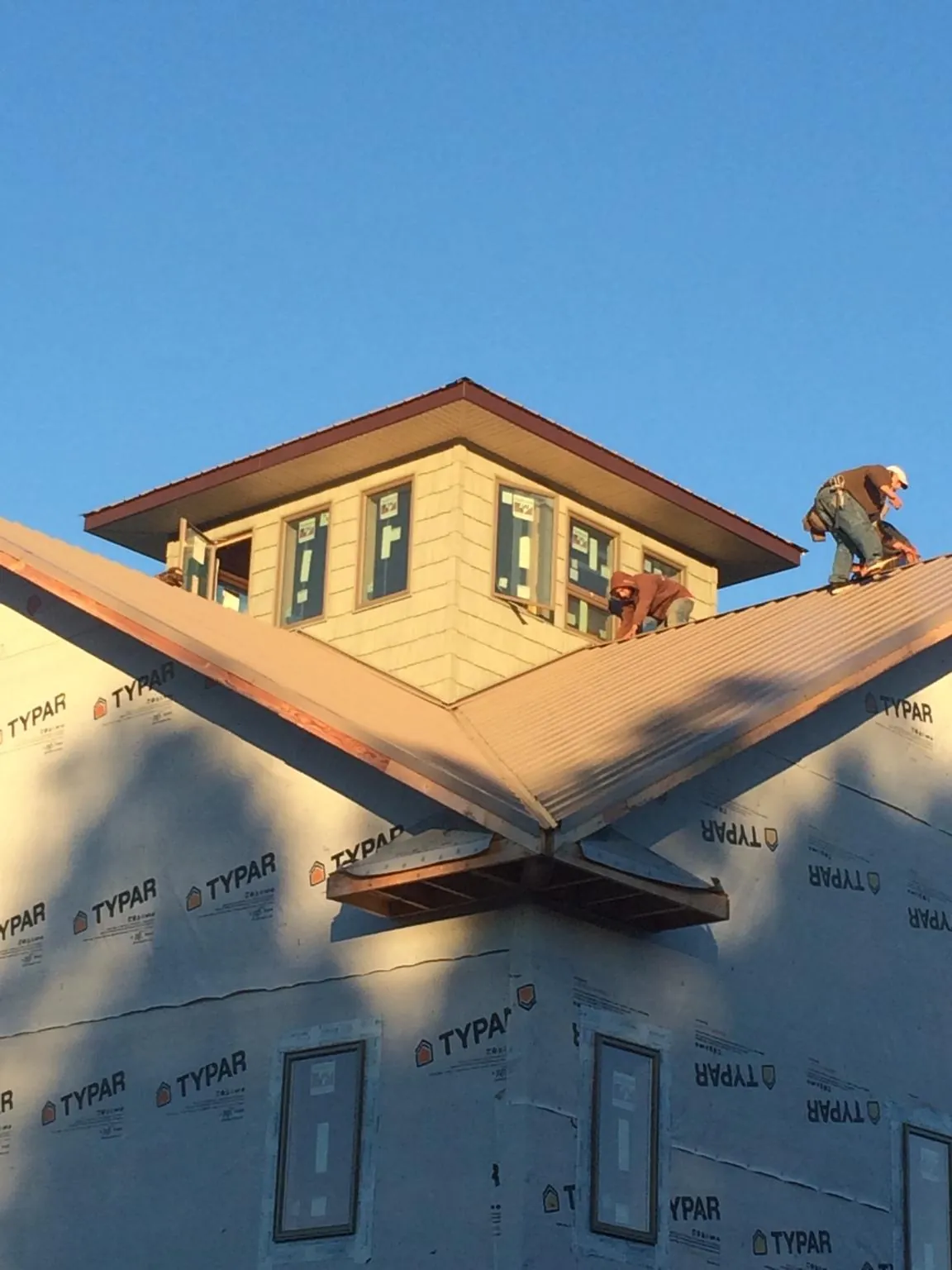 Roofers working around a rooftop cupola on a new metal roof at sunset — Roof Waterproofing in Oak Hall by Roofing Brothers